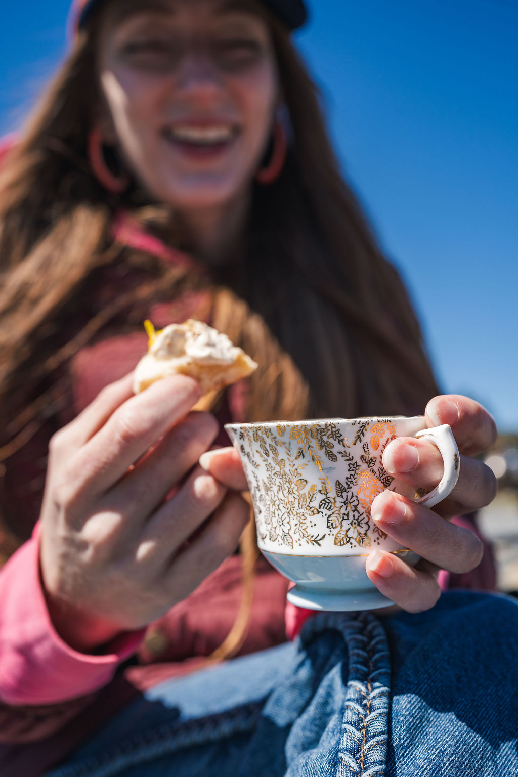 Guest holding a mug of hot tea and a homemade treat at a Newfoundland beach boil up